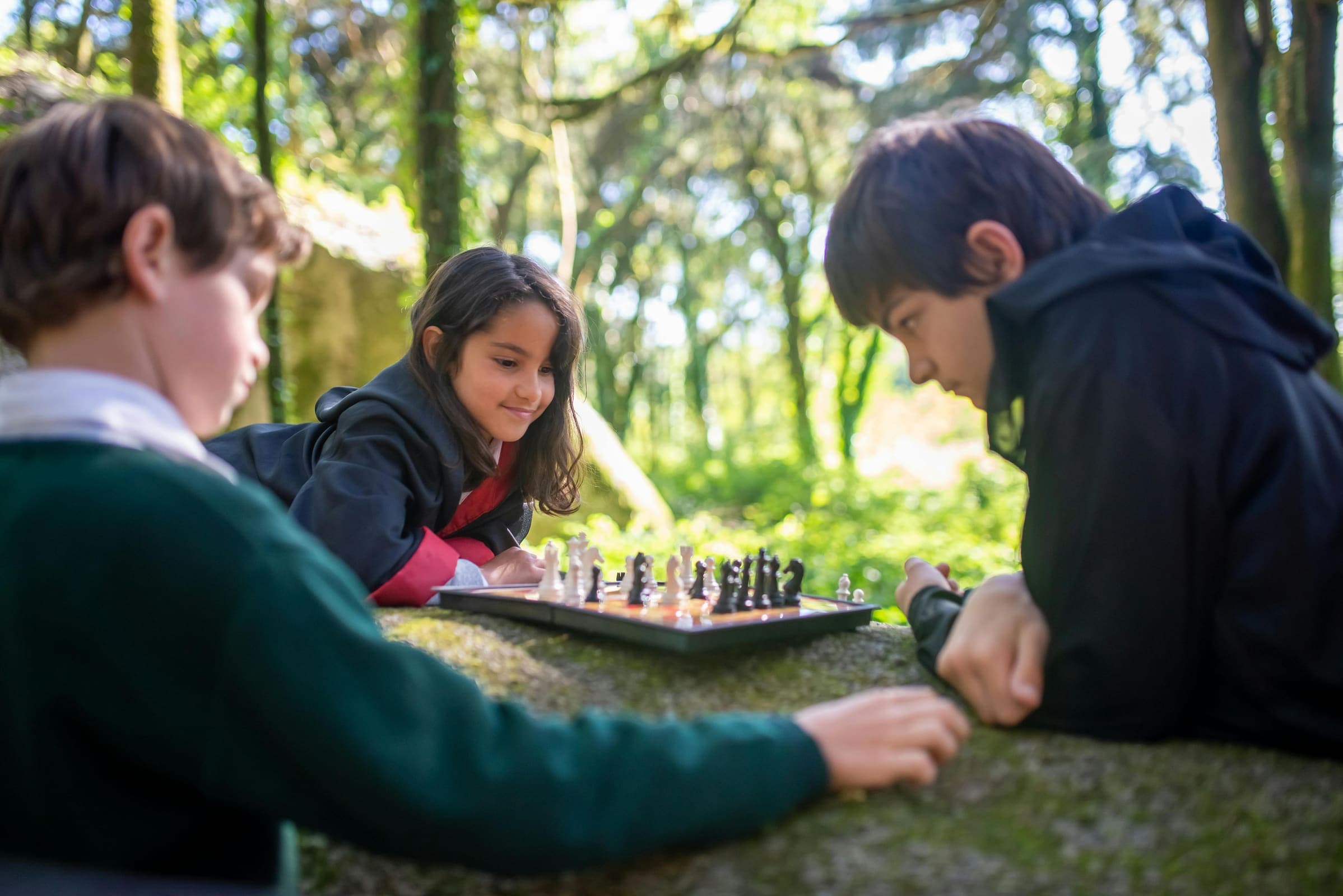 An educator and a young student working side by side outdoors.